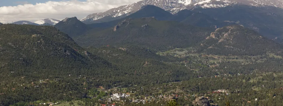 Estes Park from the Gem Lake trail: the town in its valley of pines, with snow on Longs Peak above